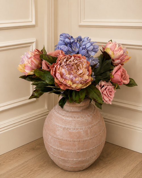 Decorative vase with colorful flowers against a neutral wall.