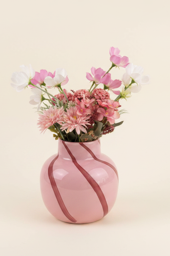 Pink cosmos and chrysanthemum arrangement in a hand-painted pink ceramic vase on a cream background